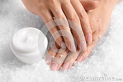 Woman holding hands near jar of cream on decorative snow. Stock Photo