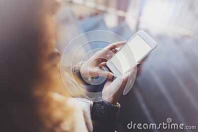 Woman holding hands smartphone and texting message.Female hands using mobile phone.Closeup on blurred background.Flares Stock Photo