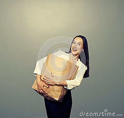 Woman holding heavy paper bag over dark Stock Photo