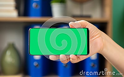 Woman holding horizontal green screen mobile phone Stock Photo