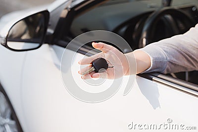 Woman holding the ignition keys of a car in her hand dangling them through the open side window Stock Photo