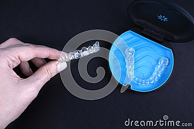 Woman holding invisible transparent aligners invisalign or plastic orthodontic braces. Black package with a box, clear Stock Photo