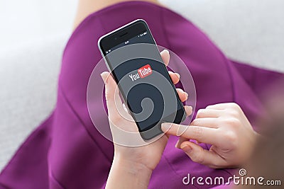Woman holding iPhone 6 with service YouTube on the screen Editorial Stock Photo