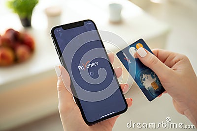 Woman holding iPhone X with payment system service Payoneer Editorial Stock Photo