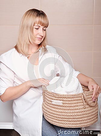 woman holding a knit jute basket with fresh towels in bathroom. housekeeping and householding using natural storage Stock Photo