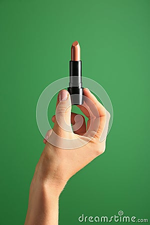 Woman holding light lipstick on color background Stock Photo