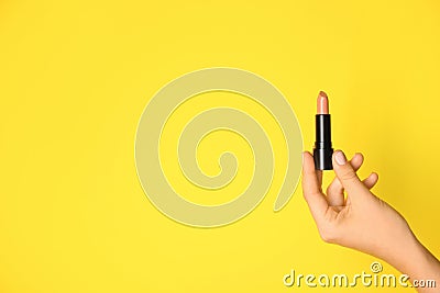 Woman holding light lipstick on color background Stock Photo