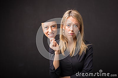 Woman holding mask of her happy face Stock Photo