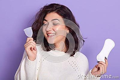 Woman holding menstrual cup and sanitary pad in hands. Feminine hygiene alternative product instead of tampon during her period. Stock Photo