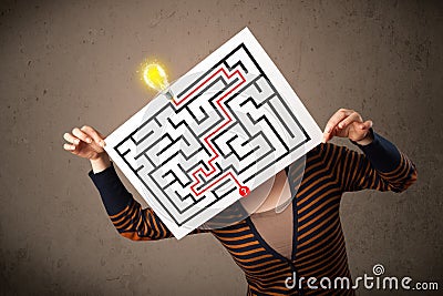 Woman holding a paper with a labyrinth on it in front of her head Stock Photo