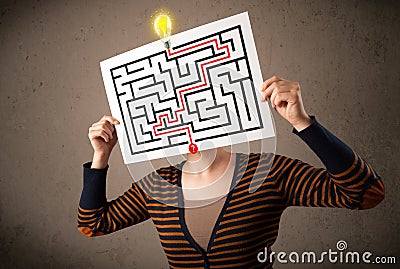 Woman holding a paper with a labyrinth on it in front of her head Stock Photo