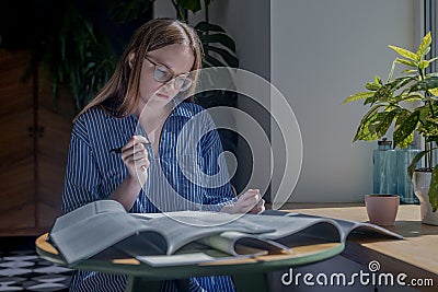 Woman holding pen and reading heap books on desk in cafe. Concept of research and searching answers in literature Stock Photo