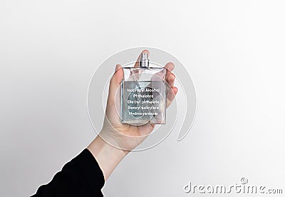 The woman is holding a perfume. Hazardous substances are indicated on the eau de toilette label. The concept of harmful components Stock Photo