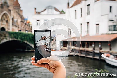 Woman holding a phone taking a photo to Bruges cityscape Stock Photo