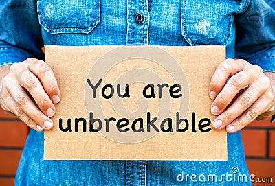 Woman holding a piece of a cardboard with words You Are Unbreakable Stock Photo