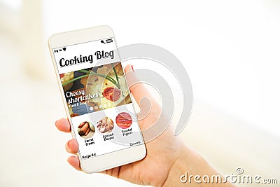 Woman holding a pink gold blank smartphone showing cooking blog Stock Photo