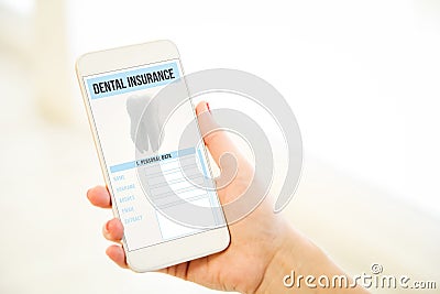 Woman holding a pink gold blank smartphone showing dental insurance Stock Photo