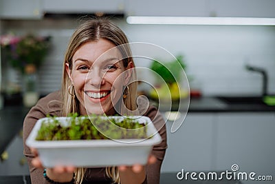 Woman holding pot with cress growing from seed at home. Stock Photo