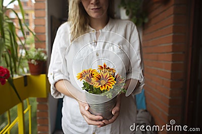 Woman holding potted colorful flowers on balcony Stock Photo