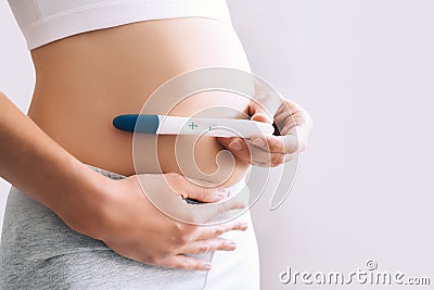 Woman holding pregnancy test in hands near her belly Stock Photo