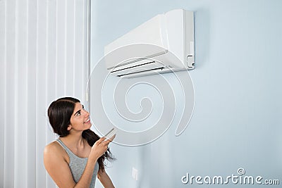 Woman holding remote control air conditioner Stock Photo