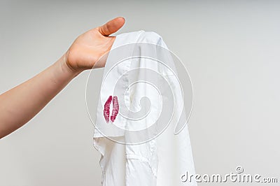 Woman holding a shirt with lipstick of her unfaithful husband Stock Photo