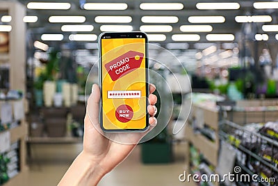 Woman holding smartphone with activated promo code in gardening store, closeup Stock Photo