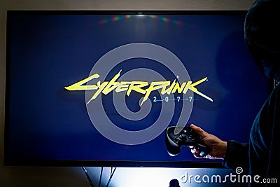 Woman holding a steam controller and playing popular video game Cyberpunk 2077 on a television and PC Editorial Stock Photo