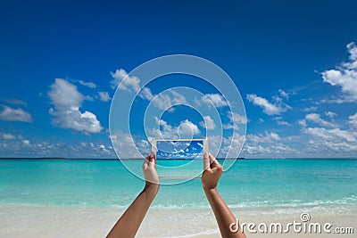 Woman holding tablet computer with screen on the tropical sea.vtravel concept - tourist photograph tropical beach on tablet pc. Stock Photo