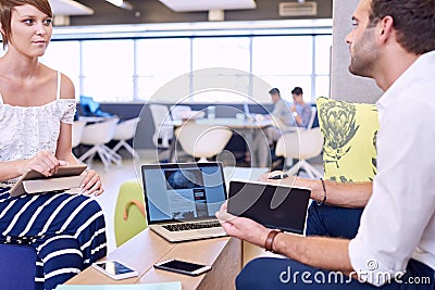 Woman holding tablet while paying attention to male business partner Stock Photo