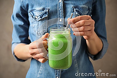 Woman holding tasty kale smoothie on brown background, closeup Stock Photo