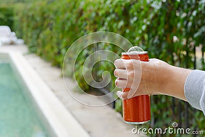 Woman holding tasty open canned beverage near swimming pool outdoors, closeup. Space for text Stock Photo