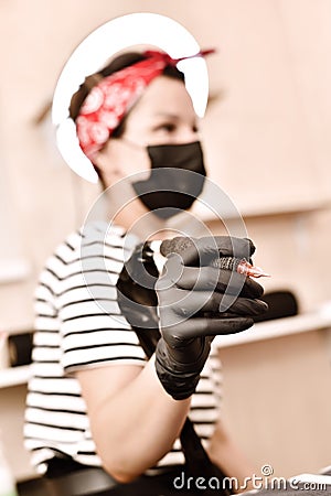 Woman holding tattoo machine in hand Stock Photo