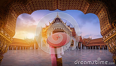 Woman holding traditional red umbrella on the Marble Temple, Wat Benchamabopitr Dusitvanaram at sunrise in Bangkok, Thailand. Stock Photo