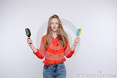 Woman holding two hairbrush posing with one half shaggy and combed hair medium shot Stock Photo