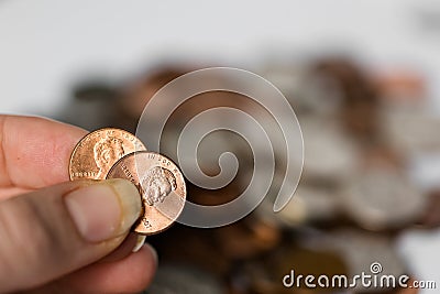 Woman Holding Two Pennies Together with Coins in Background, Penny Pinching Stock Photo