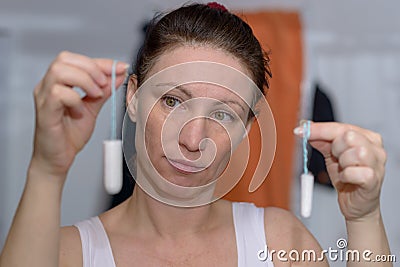 Woman holding up two tampons, one large, one small Stock Photo