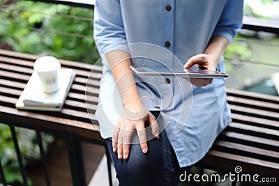 Woman holding and using tablet with books and coffee cup on office background Stock Photo