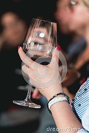 Woman holds glass of red wine. people consider the color of the wine and try how it smells in different glasses Stock Photo