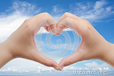 Woman holds hands up to sky in the shape of a heart Stock Photo