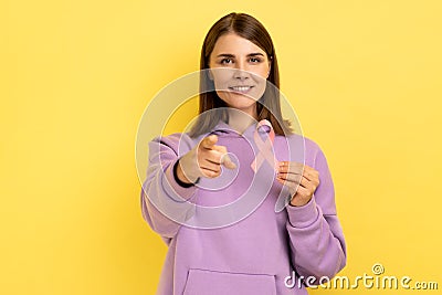 Woman holds pink ribbon near her chest supporting another women, cancer awareness pointing to camera Stock Photo