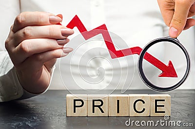 A woman holds a red arrow down over wooden blocks and the word Price. Concept of falling market value. Promotions and sale. Stock Photo