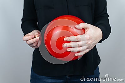 Conceptual photography. The woman holds a red ball near his belly, which symbolizes bloating and flatulence. Then she brings a nee Stock Photo