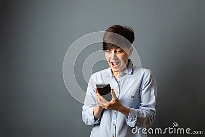 A woman holds and scans the phone, telephone conversation. Woman portrait on a gray background. Copy space Stock Photo