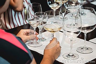 Woman holds two glasses of white wine. people consider the color of the wine and try how it smells in different glasses Stock Photo