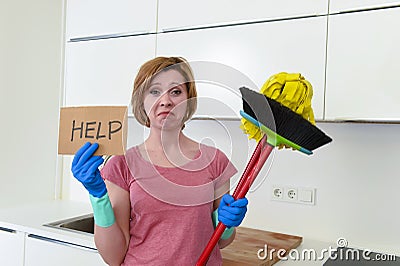 Woman at home kitchen in gloves with cleaning broom and mop asking for help Stock Photo