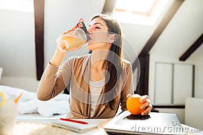 Woman in home office drinking orange flavored amino acid vitamin powder.Keto supplement.After exercise liquid meal.Weight loss Stock Photo