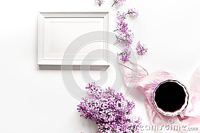 woman home office with lilic flowers frame and cup of coffee white desk background top view mock up Stock Photo