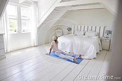 Woman At Home Starting Morning With Yoga Exercises In Bedroom Stock Photo