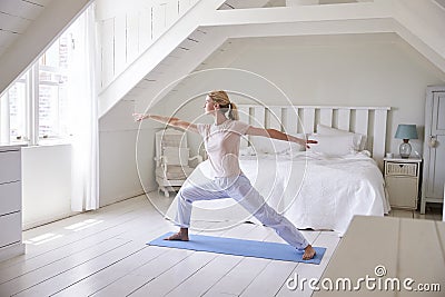 Woman At Home Starting Morning With Yoga Exercises In Bedroom Stock Photo